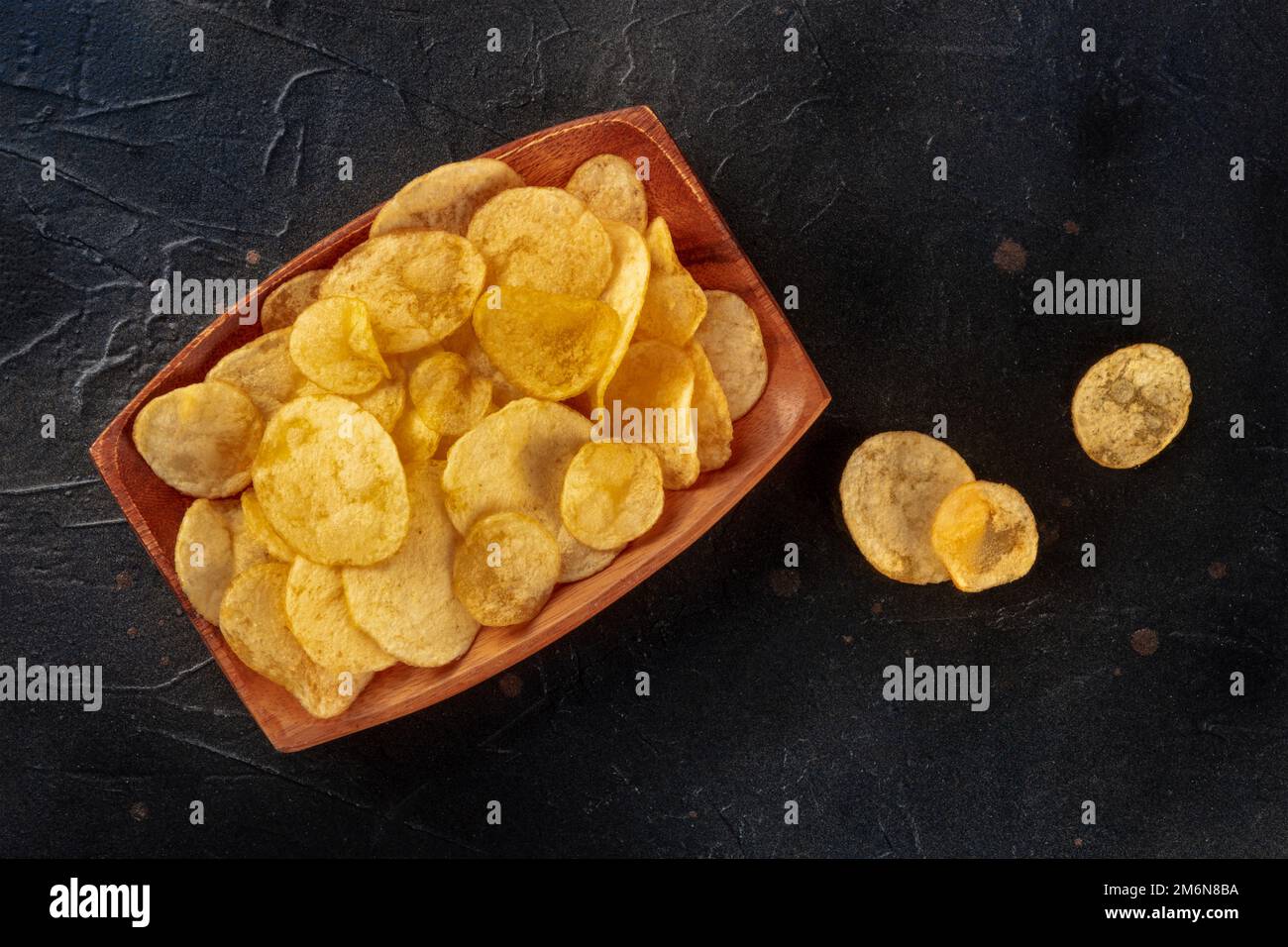 Potato chips or crisps, a salty snack, shot from the top on black Stock