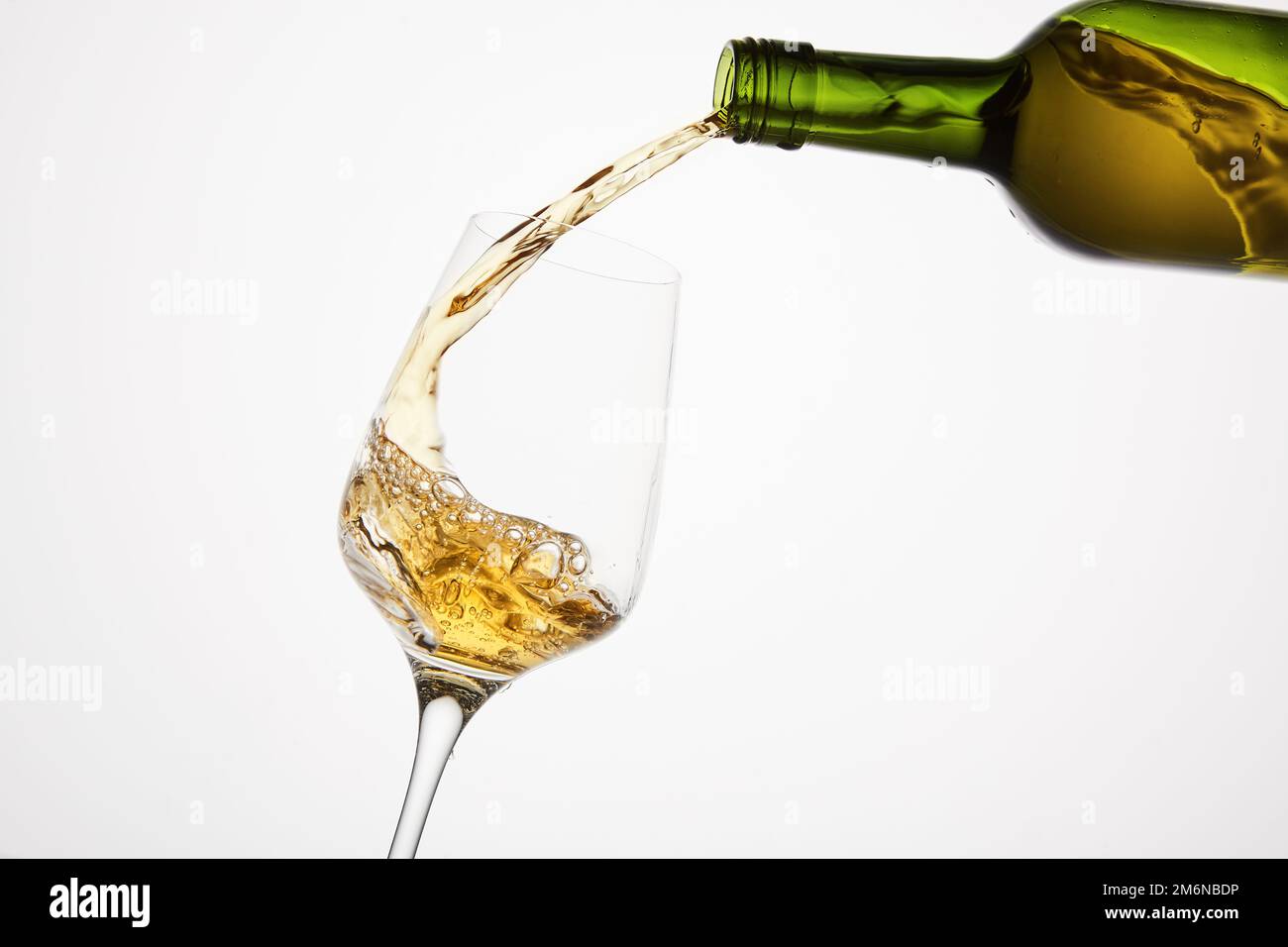 White wine pouring from green bottle, close up shot on white isolated