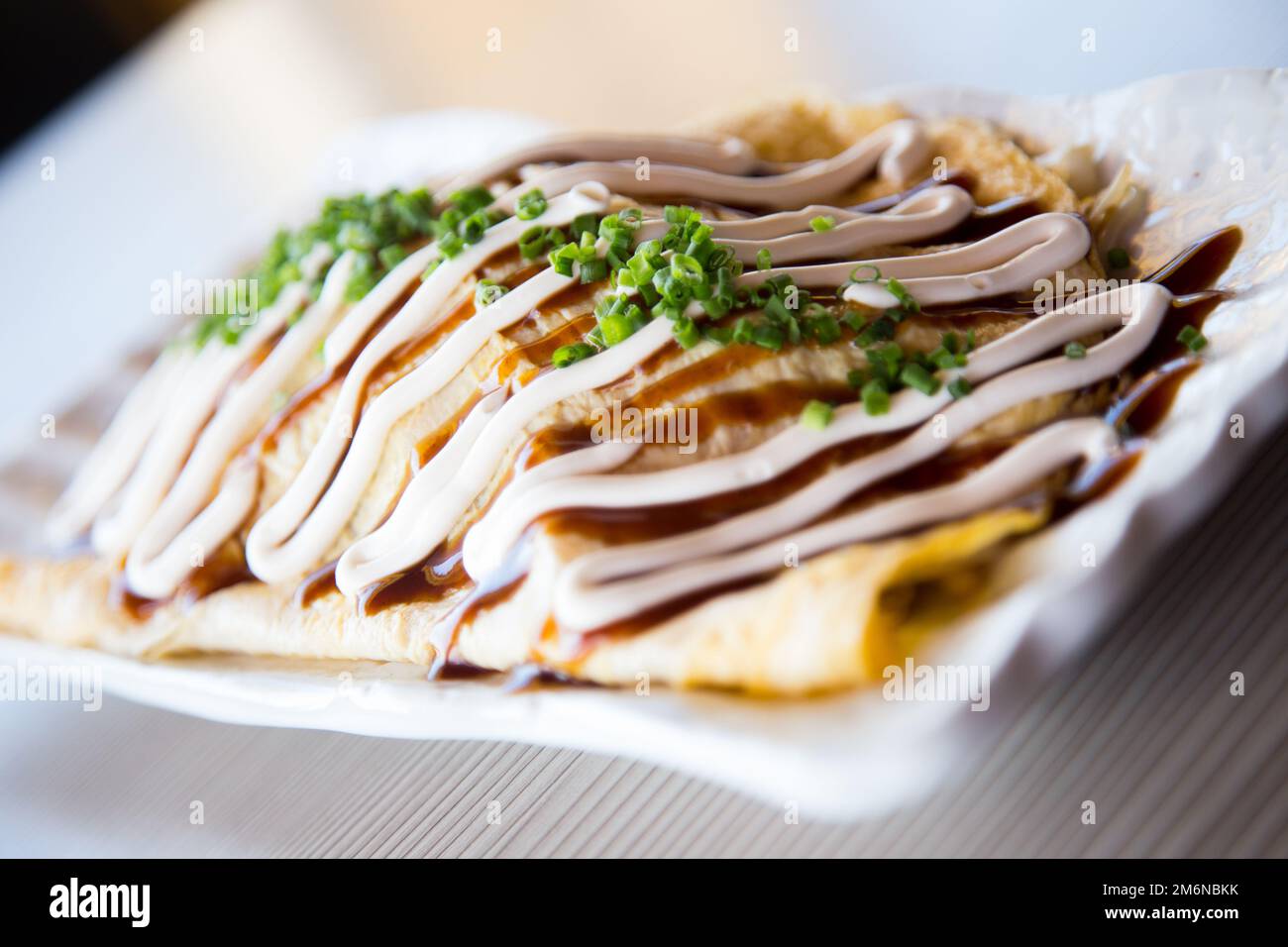 Japanese rice omelette stuffed with vegetables, meat and covered with various sauces. Stock Photo