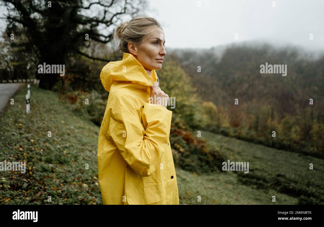 Pretty woman in yellow raincoat walking in rainy weather in the ...