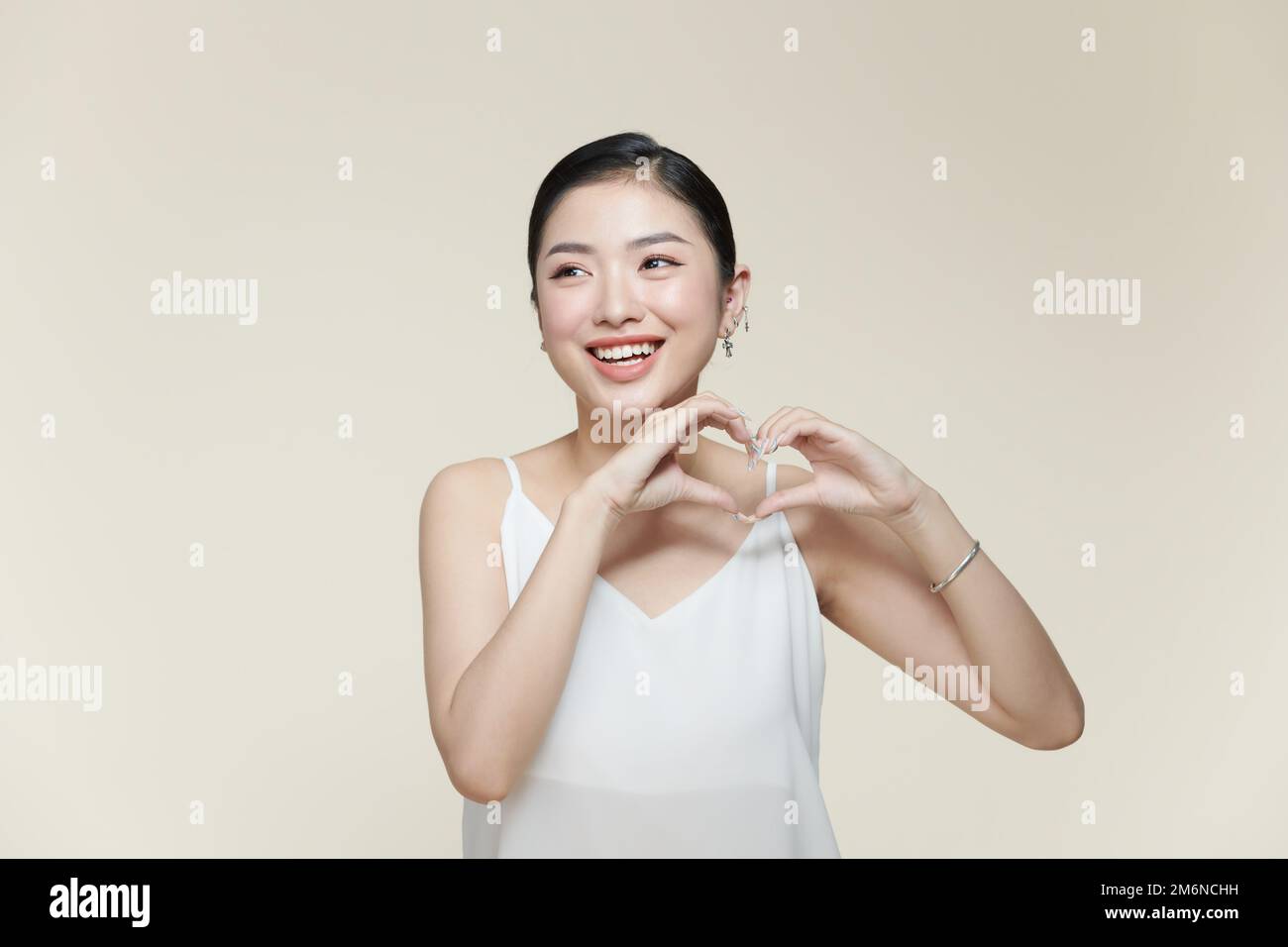 young pretty girl smiling and feeling happy, making heart shape with both hands Stock Photo