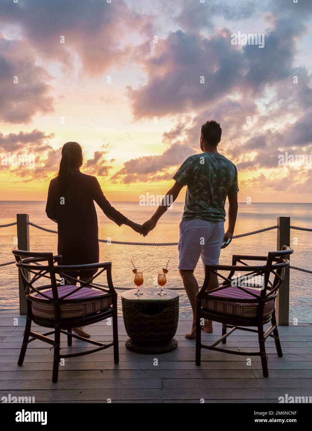 Couple drinking cocktails during sunset at the tropical beach of Saint