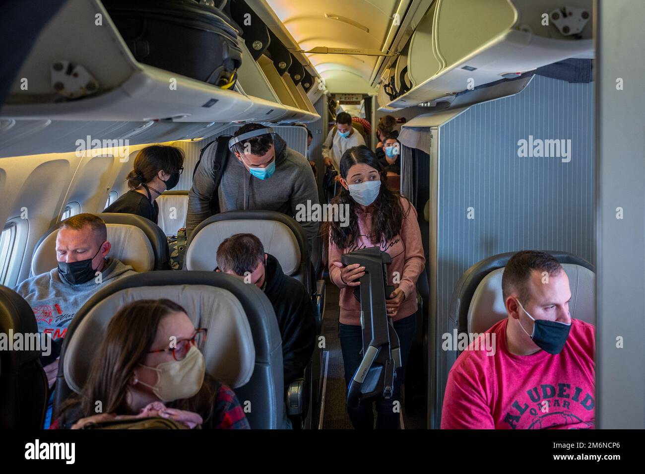 Passengers prepare to exit the aircraft after landing at Osan Air Base, Republic of Korea, May 2, 2022. Mask-wear is still mandatory in all DoD transportation assets, regardless of vaccination status. Stock Photo