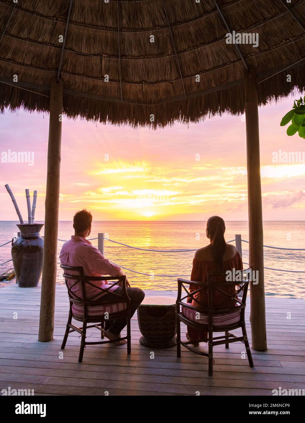 Couple drinking cocktails during sunset at the tropical beach of Saint