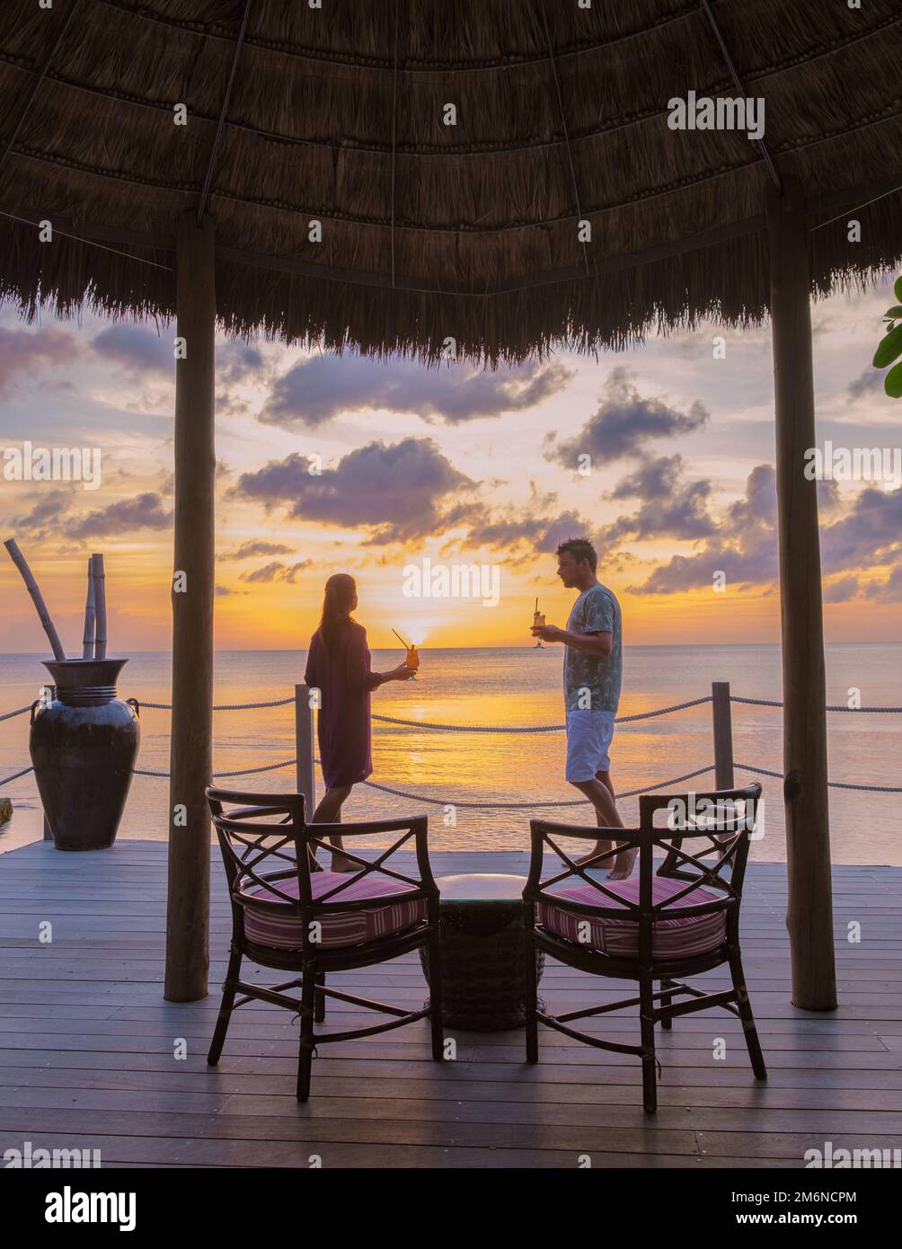 Couple drinking cocktails during sunset at the tropical beach of Saint