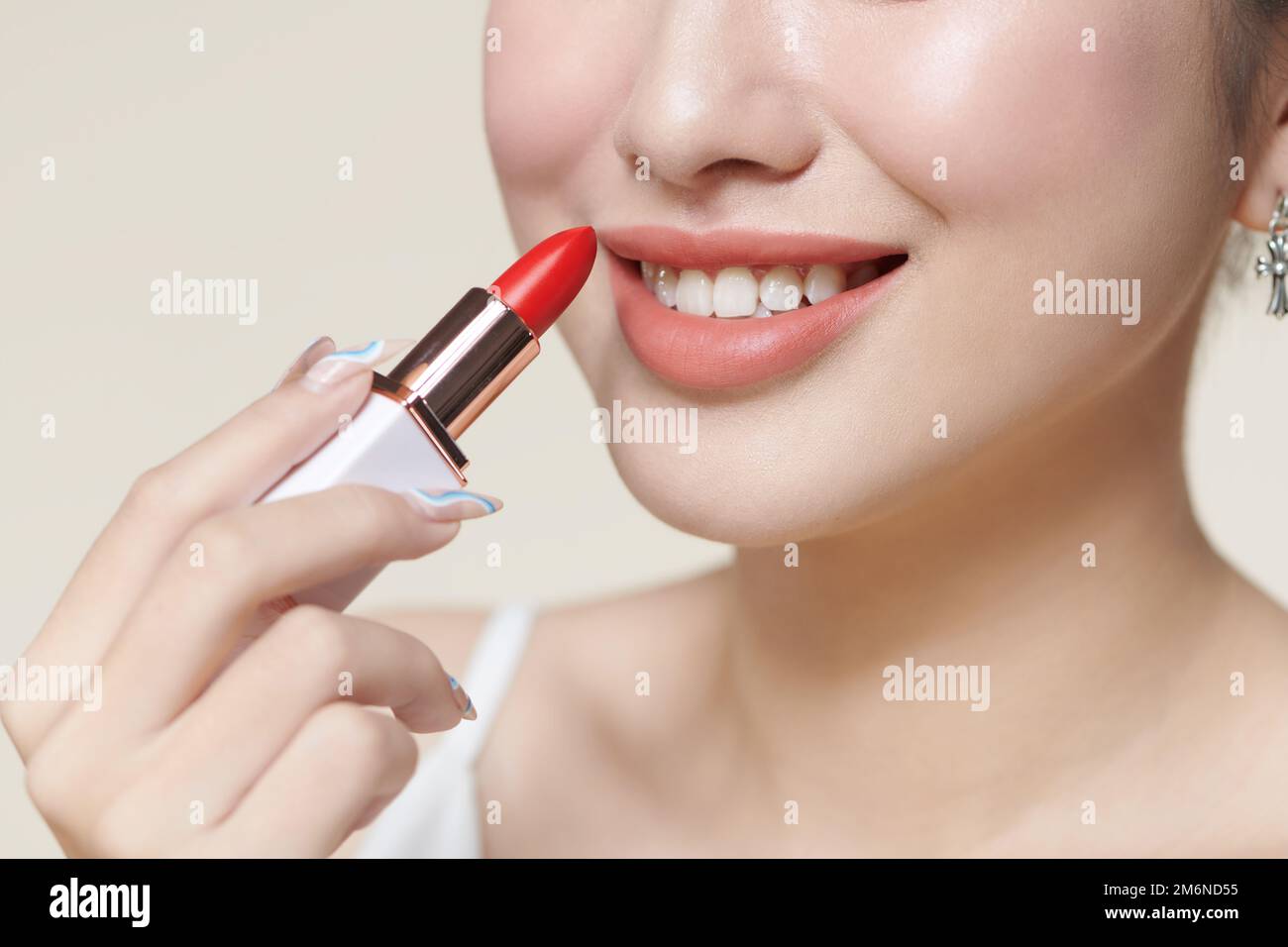 Portrait of gorgeous smiling woman holding red lipstick in hand Stock Photo