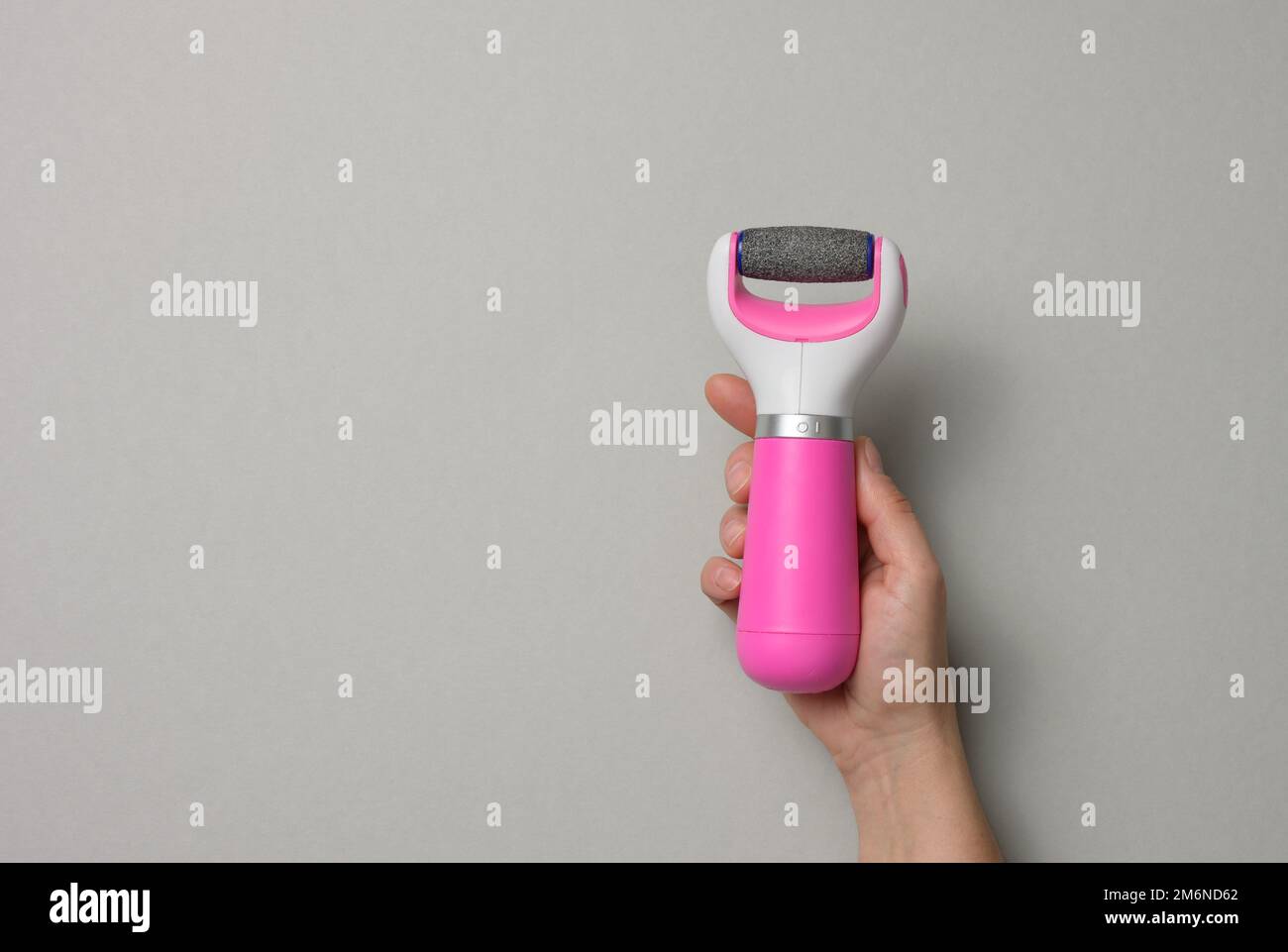 Woman's hand holding an electric pedicure tool on a gray background Stock Photo