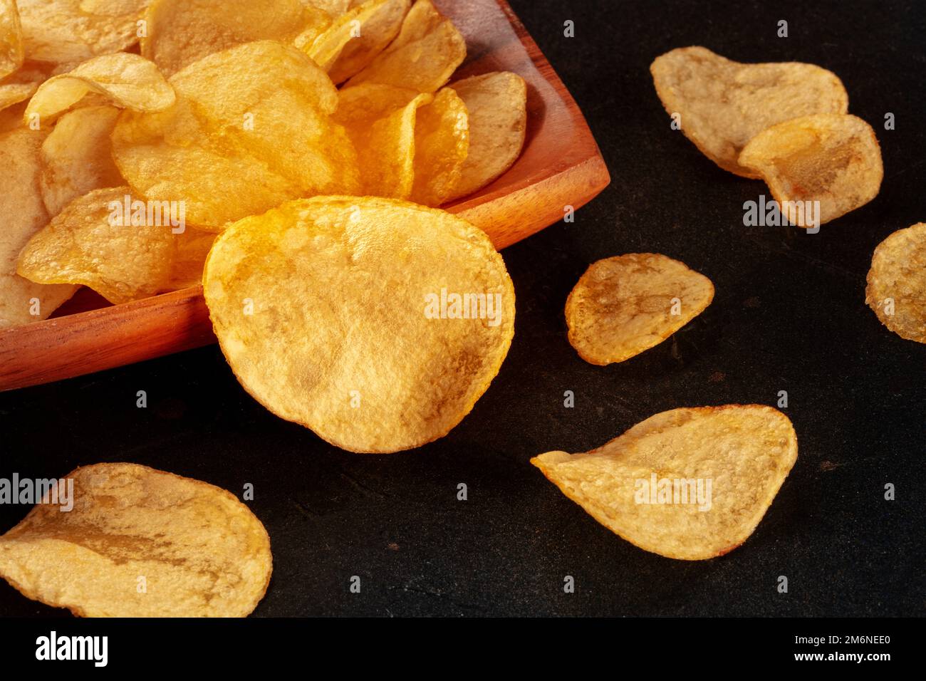 Potato chips or crisps in a bowl and scattered on black Stock Photo Alamy