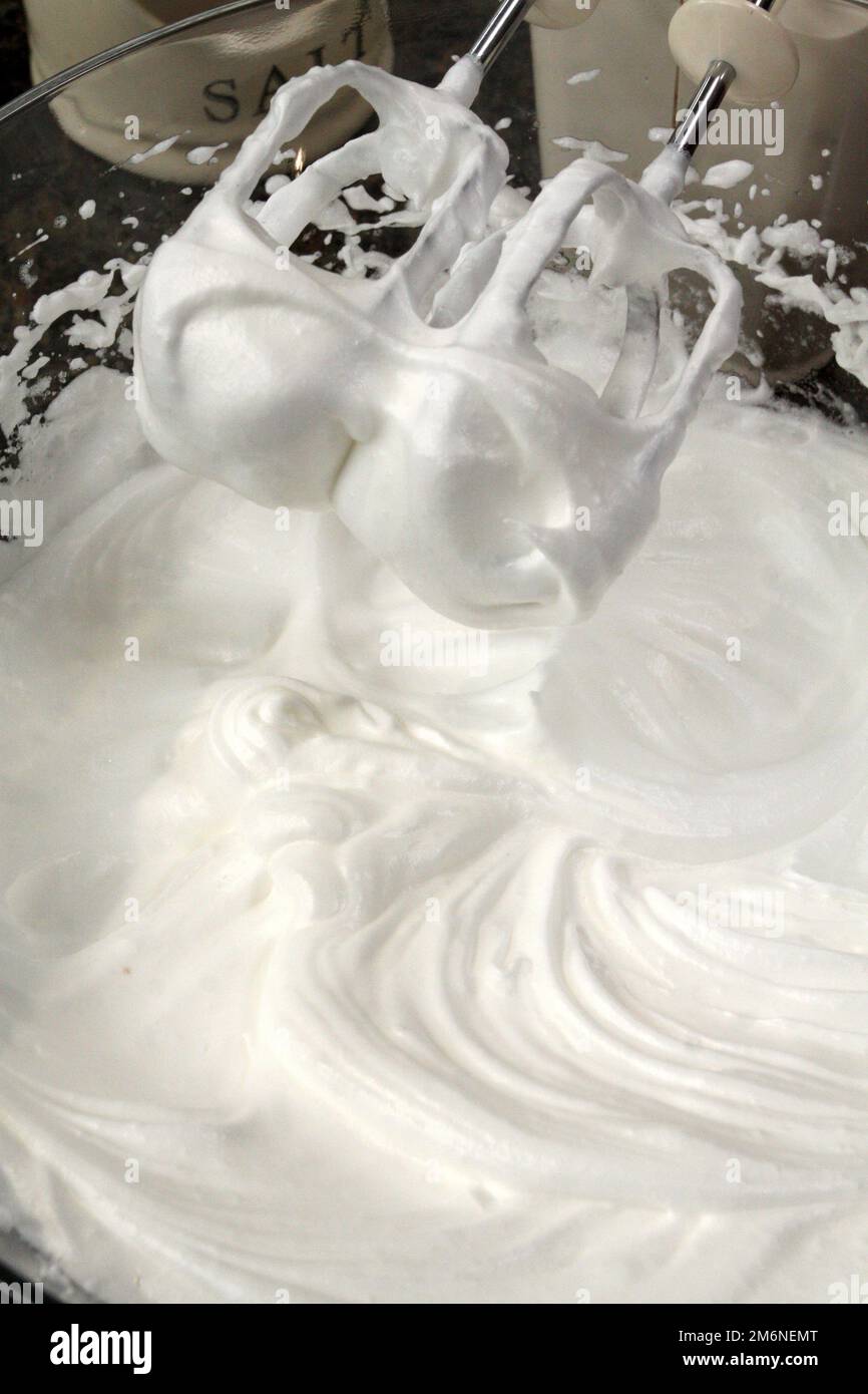 Mixer beaters in whipped egg whites that have just been beaten until they are stiff. Stock Photo