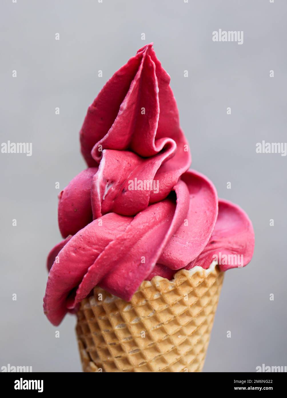 A waffle ice cream cone filled with a delicious freshly made raspberry soft serve ice cream. Stock Photo