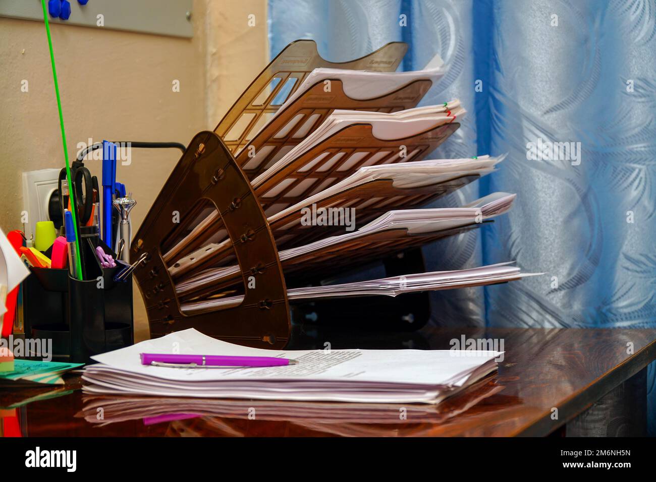 Plastic organizer for documents on the office desk. The pink pen lies on business papers, documents Stock Photo