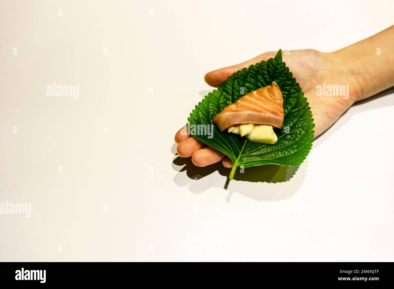 Korean ssam, sliced salmon and garlic on the fresh sesame leaf, perilla