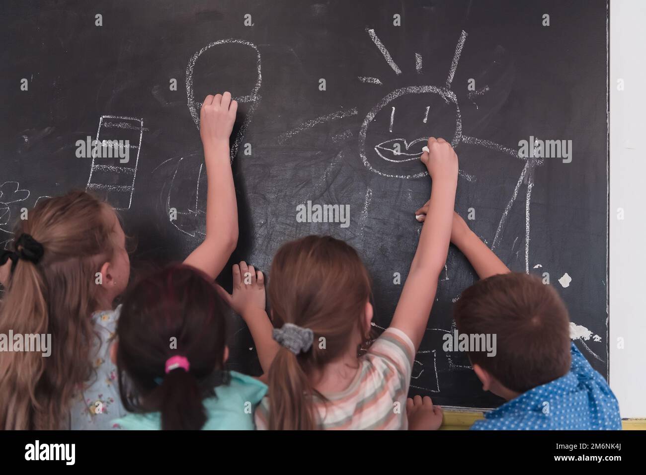 Children write and draw on the blackboard in elementary school while
