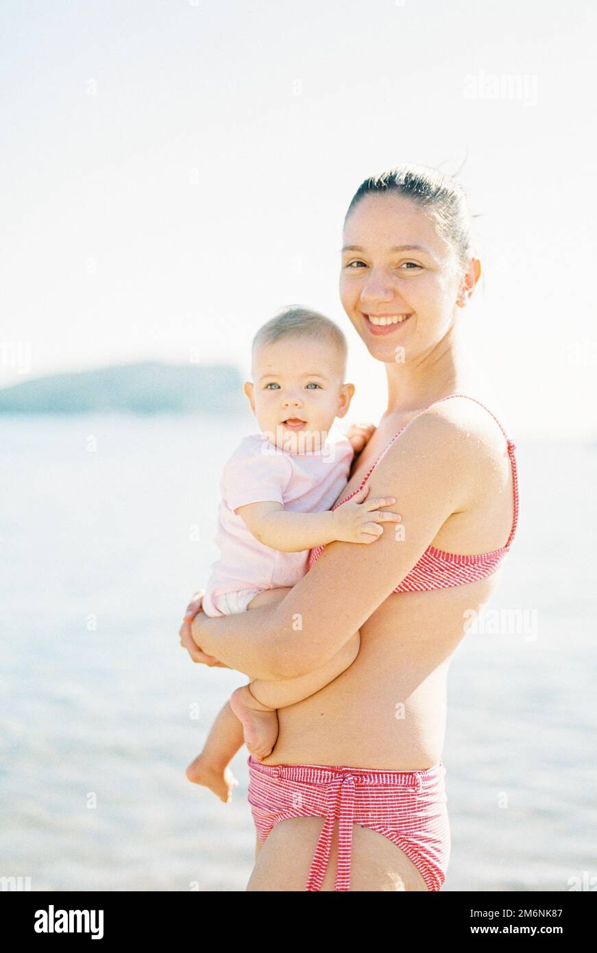 Mom with a child in her arms is standing by the sea Stock Photo