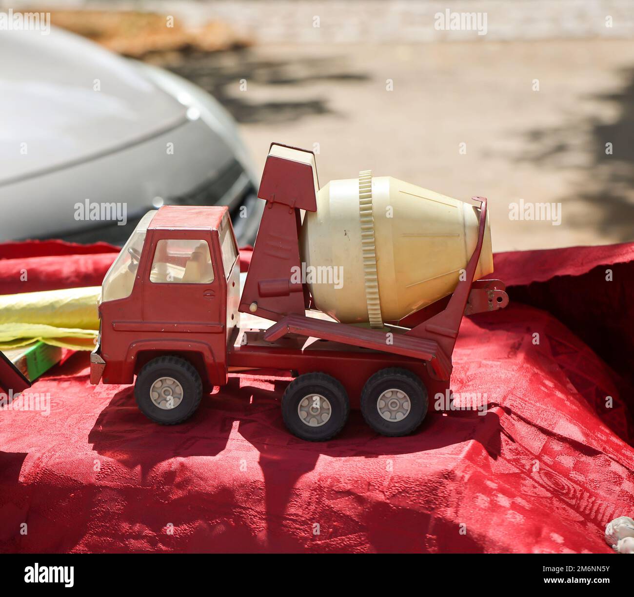 On a table is a red and yellow toy car, a concrete mixer truck. Toys for children Stock Photo