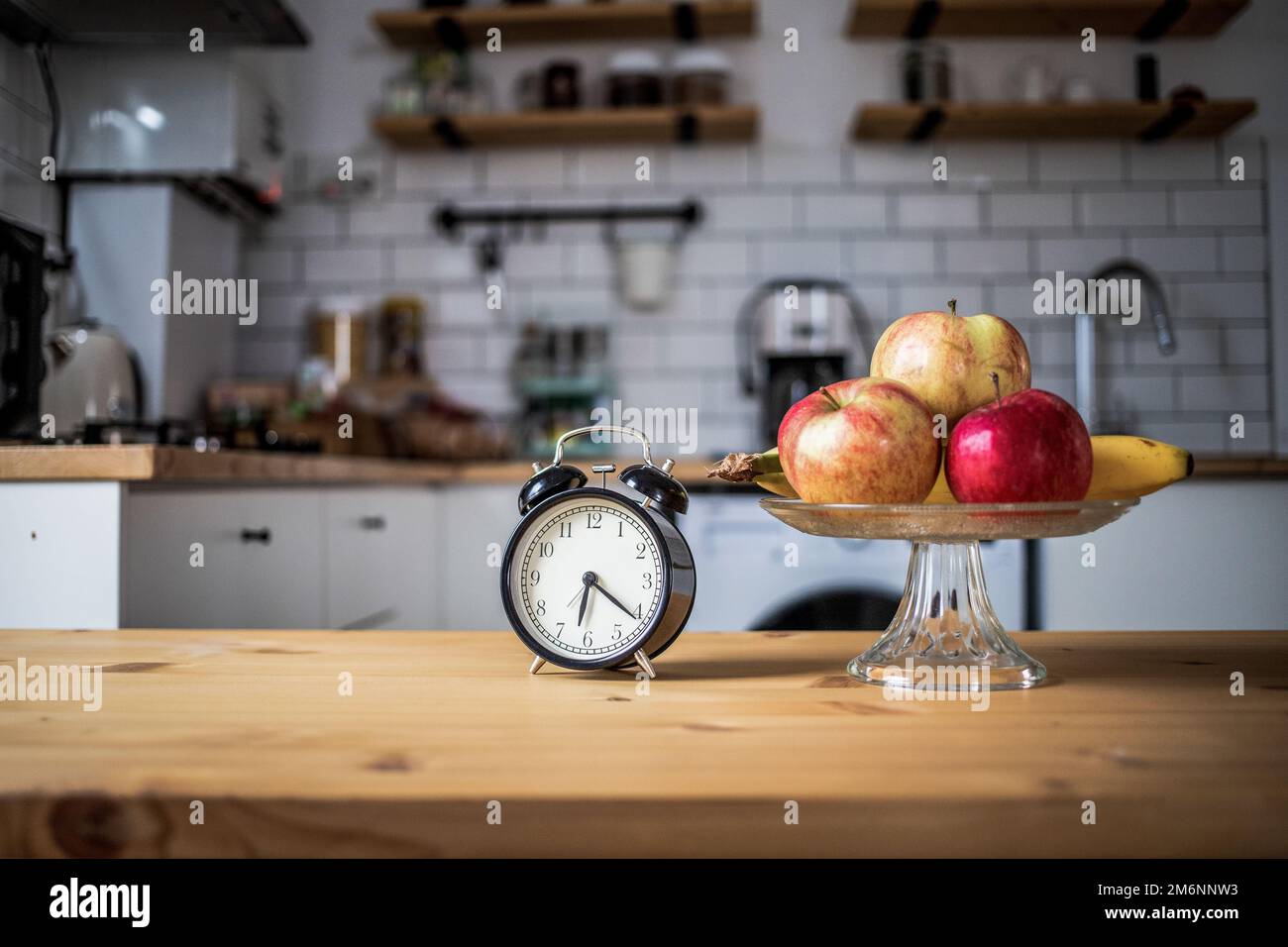 Vintage alarm clock and fresh fruit on kitchen table intermittent fasting Stock Photo