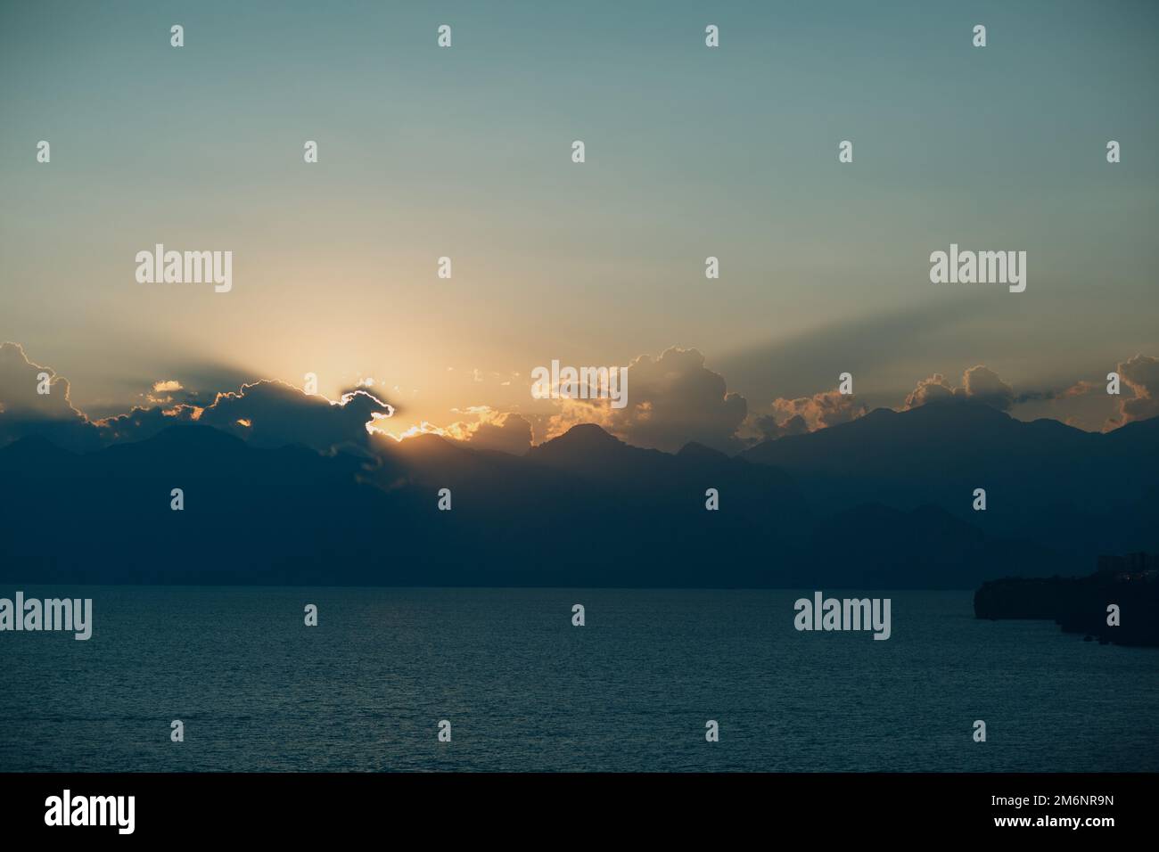 Dramatic sunset rays through cloudy dark sky over the ocean Stock Photo