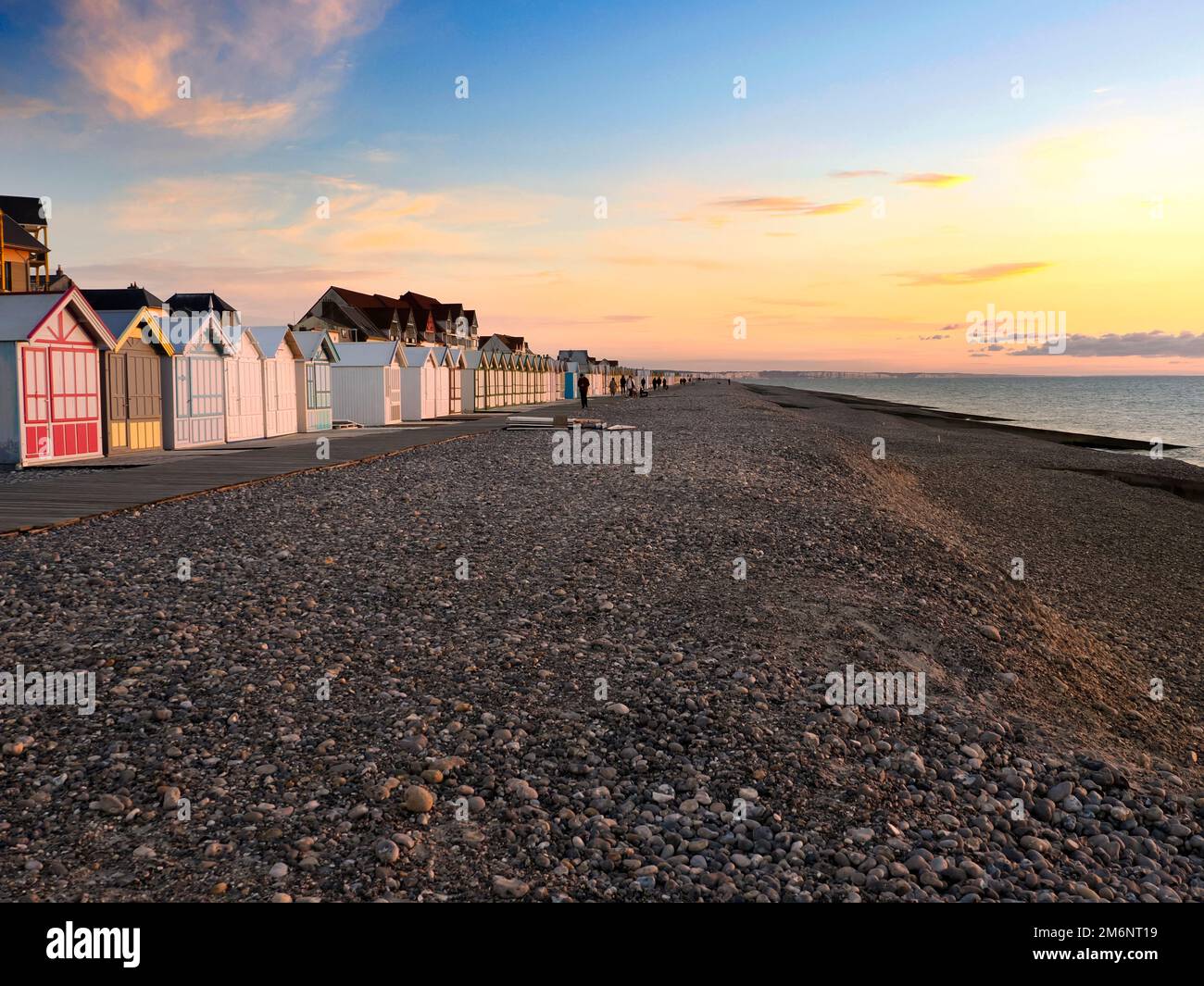 Beach cabins and pebble beach in the evening at sunset at Cayeux sur Mer, a resort town in the Somme department in Hauts-de-France in northern France. Stock Photo