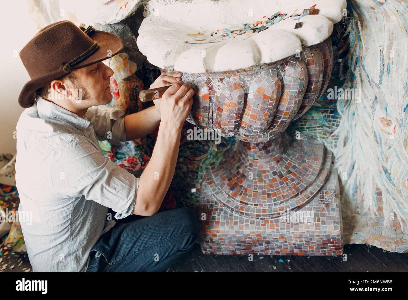 Man mosaics master making smalt glass mosaic panel. Male mosaicist at work. Stock Photo