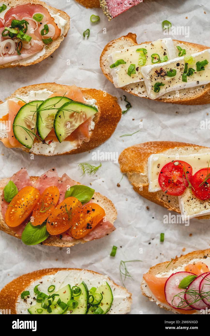 Variety of small sandwiches with cream cheese, vegetables and salami. Stock Photo