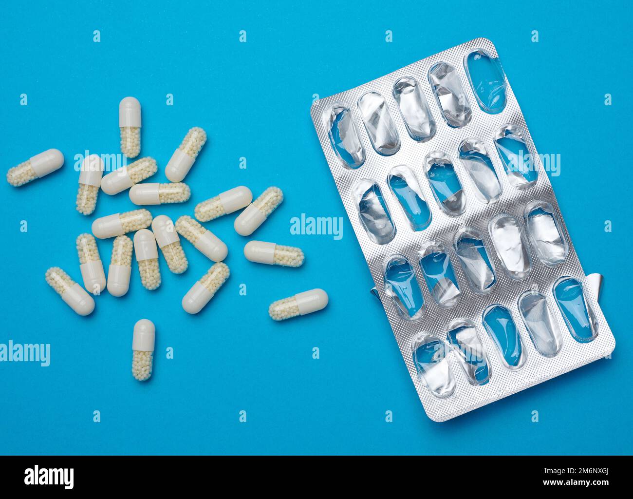 White oval pills and blank blister pack on blue background Stock Photo