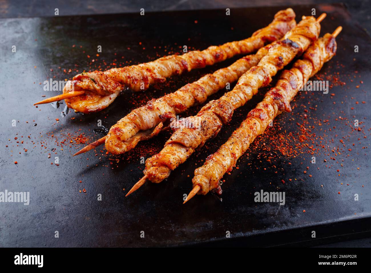 Traditional grilled torches with bacon and spicy marinade wrapped around a wooden skewer and served as a close-up on a rustic bo Stock Photo