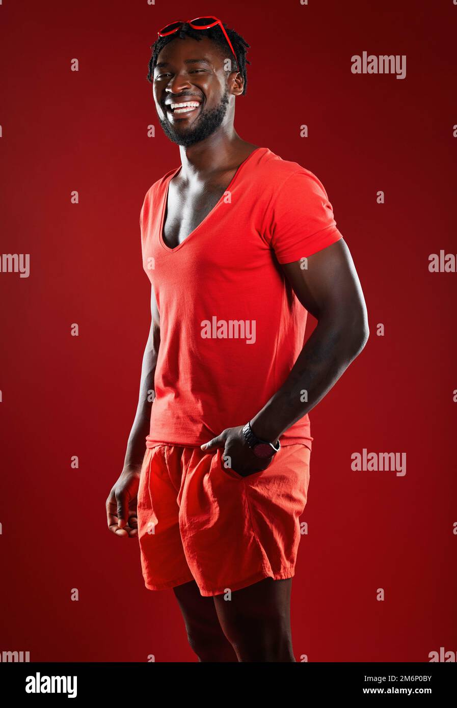 Black man, studio portrait and sport clothes with smile, sunglasses or happiness by red background. Model, man and happy with summer fashion, beauty Stock Photo