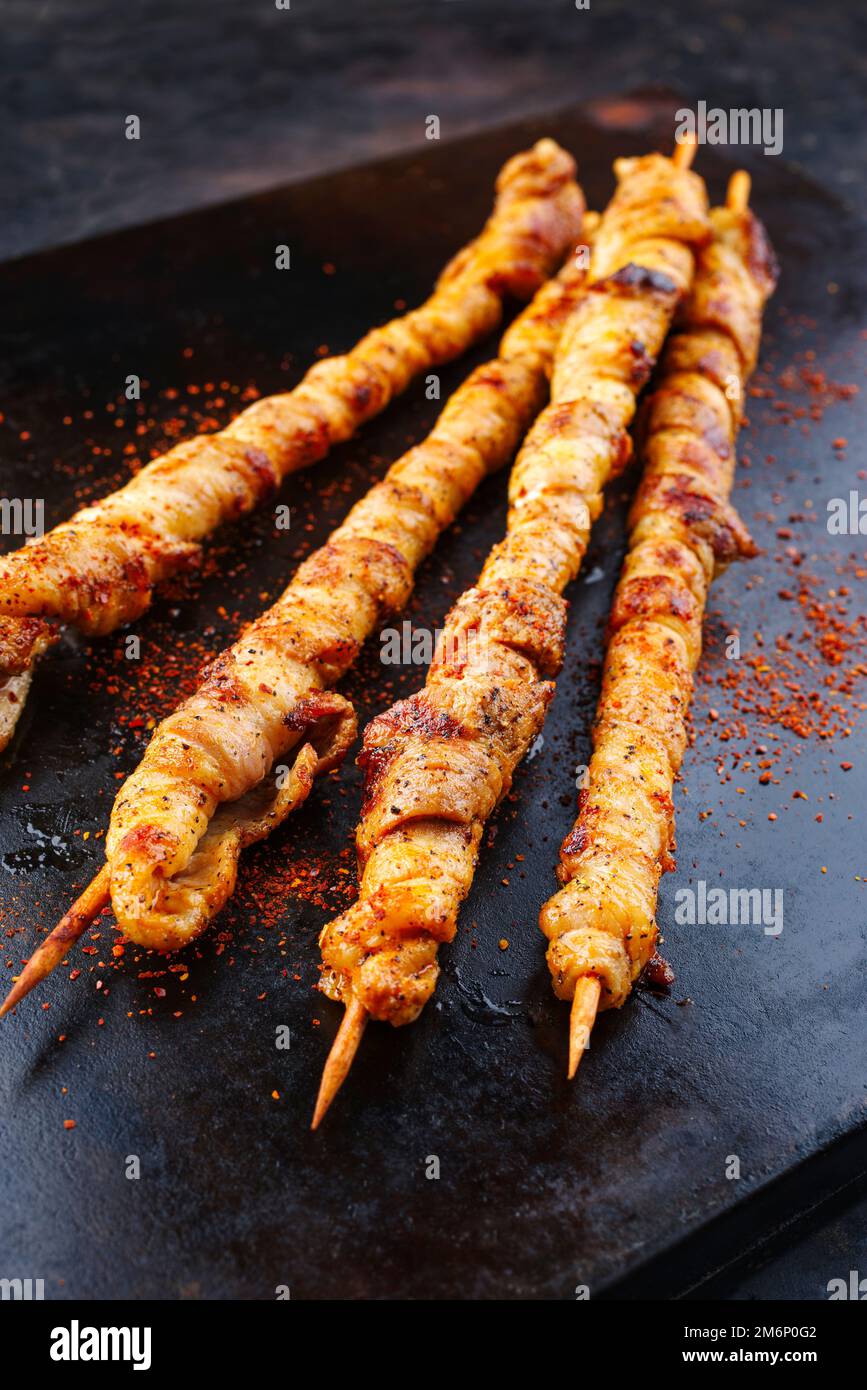 Traditional grilled torches with bacon and spicy marinade wrapped around a wooden skewer and served as a top view on a rustic bo Stock Photo