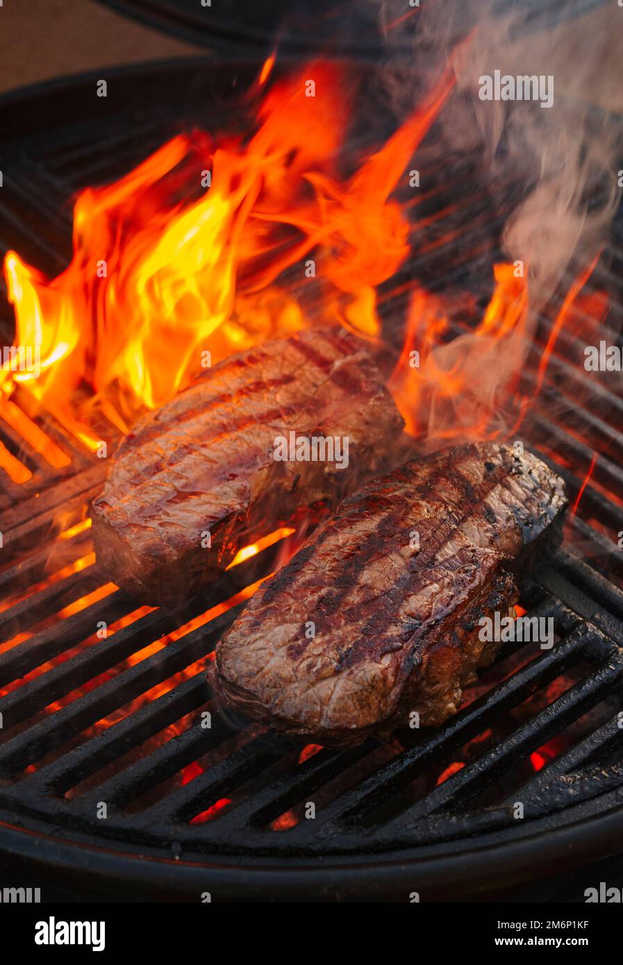 BBQ dry aged wagyu roast beef steak grilled as closeup on a charcoal grill with fire and smoke