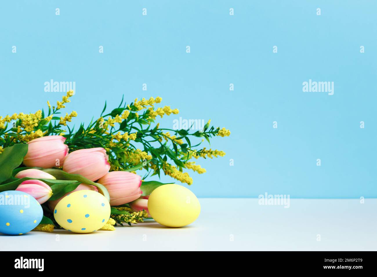 Spring composition. Blooming branch flowers tulips easter eggs on the table. Stock Photo