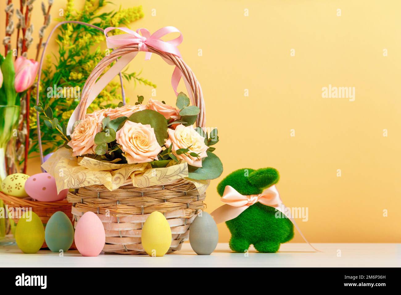 Easter still life. A basket with flowers and eggs, a toy rabbit on the table. copy space Stock Photo