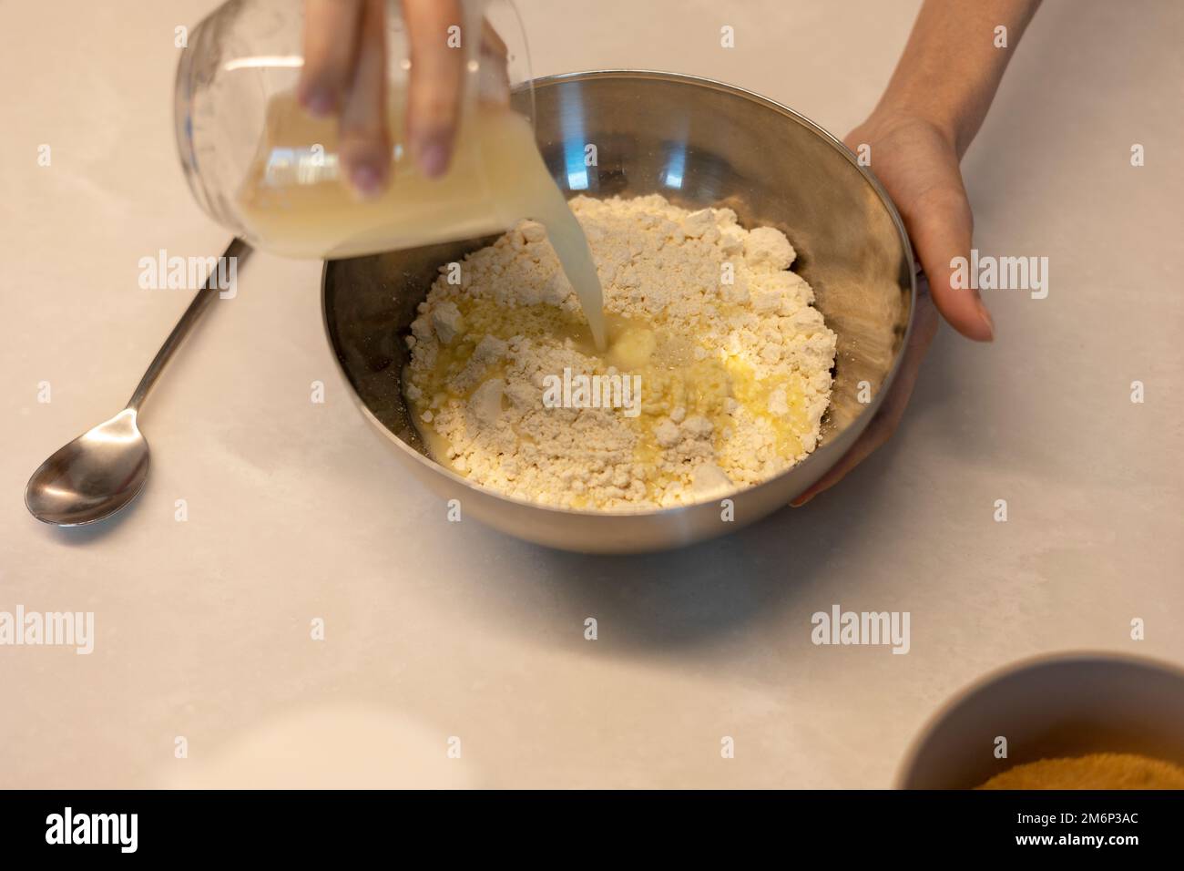 Making cookie bread hotteok dough before baking, pouring yeast water and mixture into a paste by hands Stock Photo