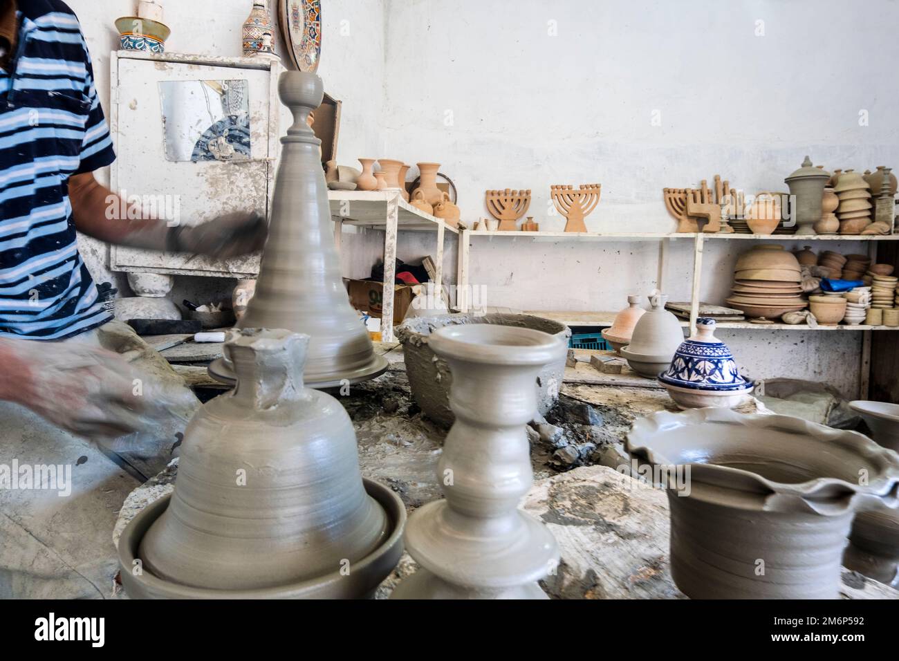Skillful potter forming a vessel out of gray clay in a pottery factory