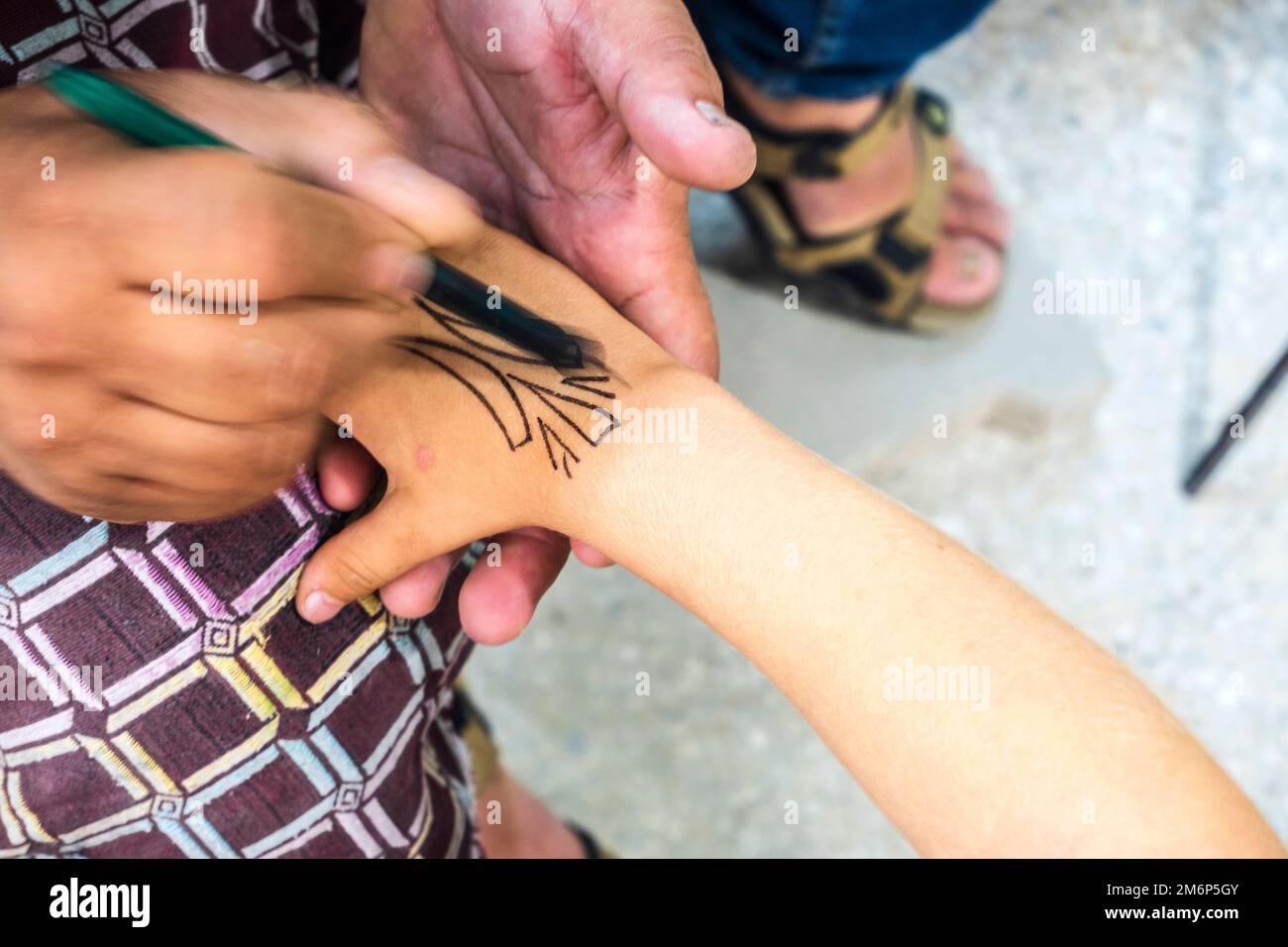 Craftsman decorating small tourist's hand in pottery factory in Fez, Morocco, North Africa Stock Photo