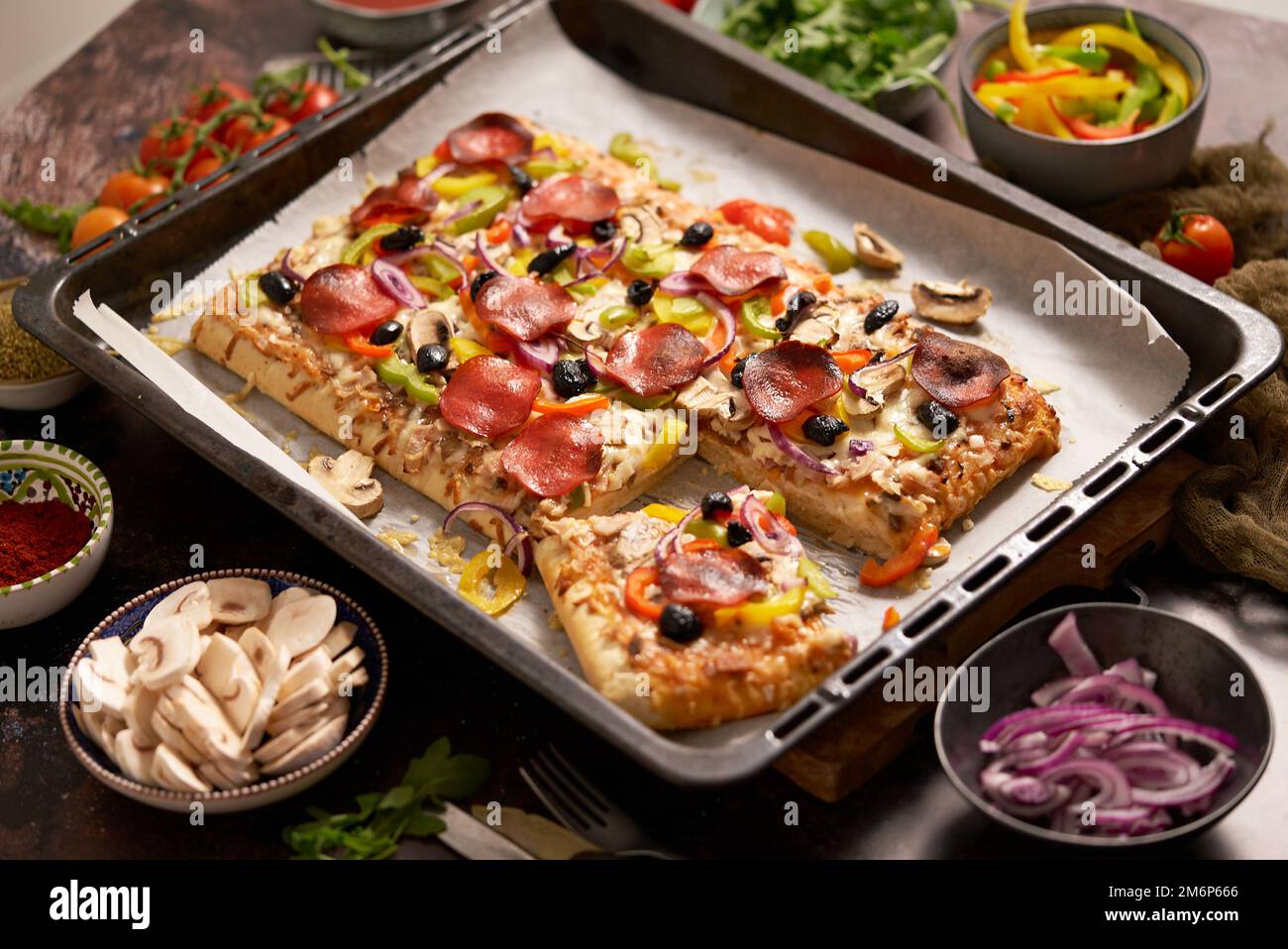 A piece of square pizza with basil pepperoni tomatoes and mushrooms on a iron tray Stock Photo