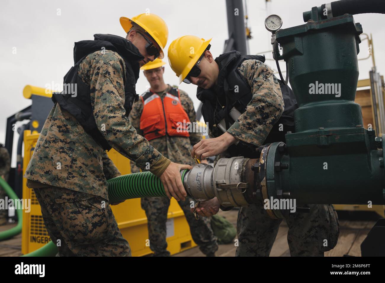 U.S. Marine Corps Pfc. Tyler Wagner (left) and Cpl. Austin Meixner, both bulk fuel specialists with Bulk Fuel Company, 7th Engineer Support Battalion, 1st Marine Logistics Group, attach a hose to a water pump during tactical bulk fuel operations aboard the Ocean Valor on May 3, 2022. Demonstrations of both existing and new bulk liquid distribution systems were utilized to aid development of fuel distribution in contested littoral environments. Stock Photo