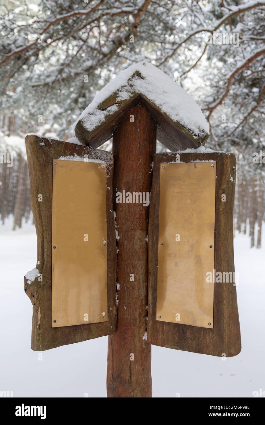 Wooden blank sign in winter forest, with cooper plates and copyspace for your text. Advertising space Stock Photo