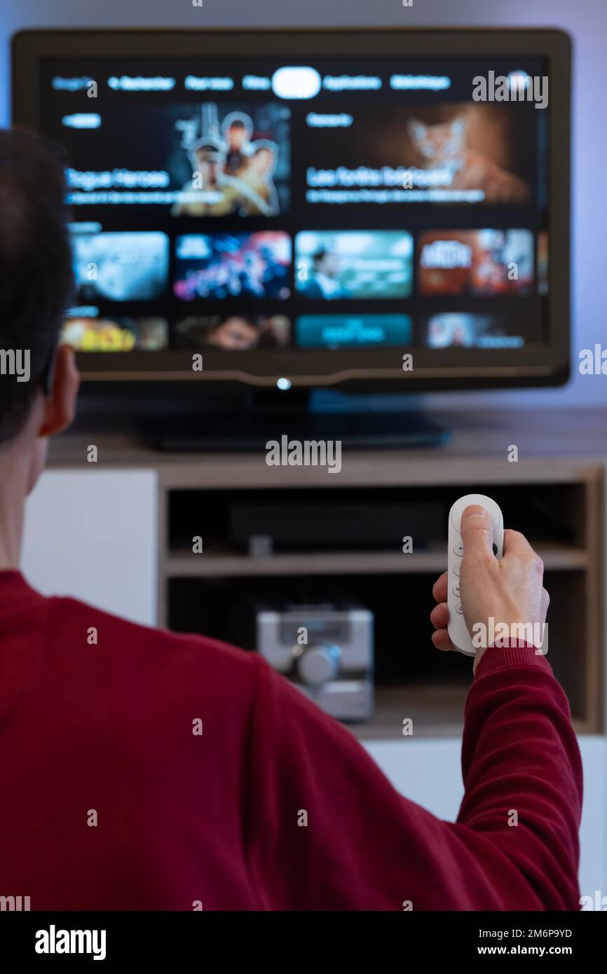 A man from behind with a remote control, choosing a program on