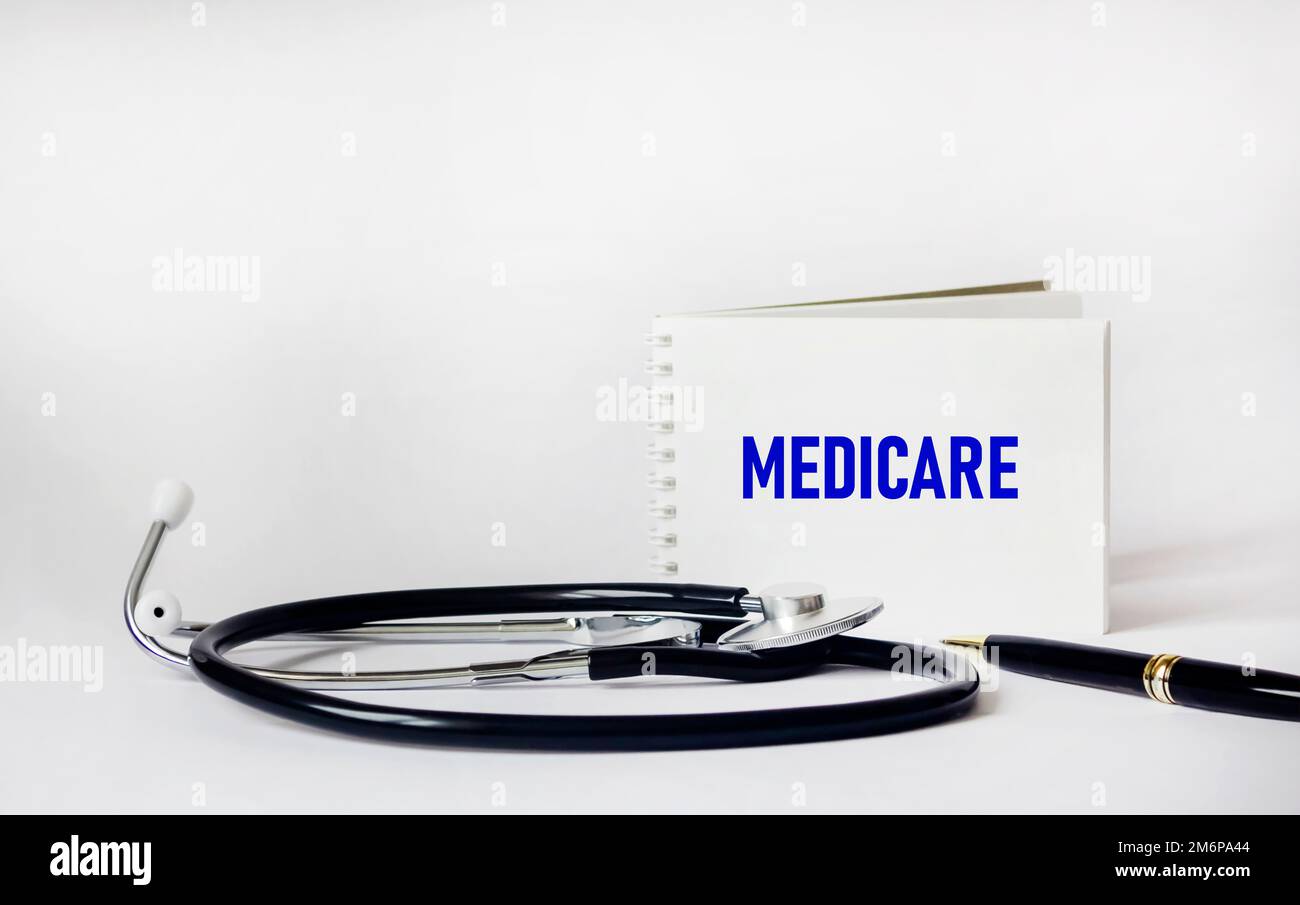 The word Medicare is written on a notepad on a white background with a stethoscope and a pen Stock Photo