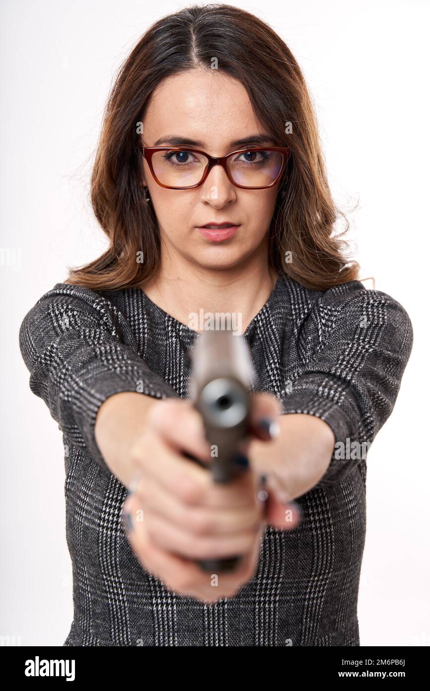Businesswoman in reading glasses with serious expression pointing a gun ...