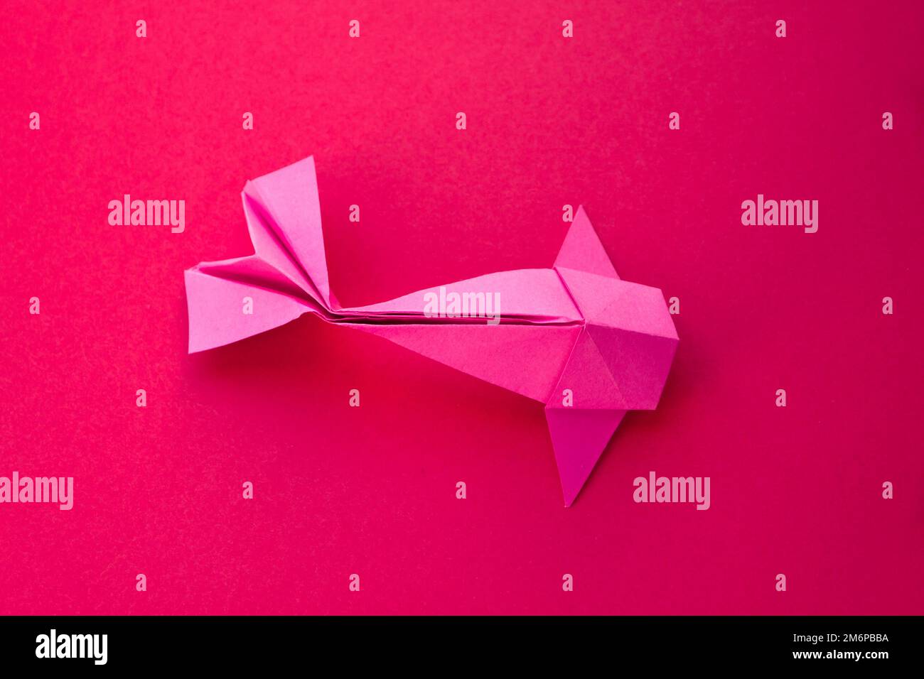 Pink paper fish origami isolated on a red background Stock Photo