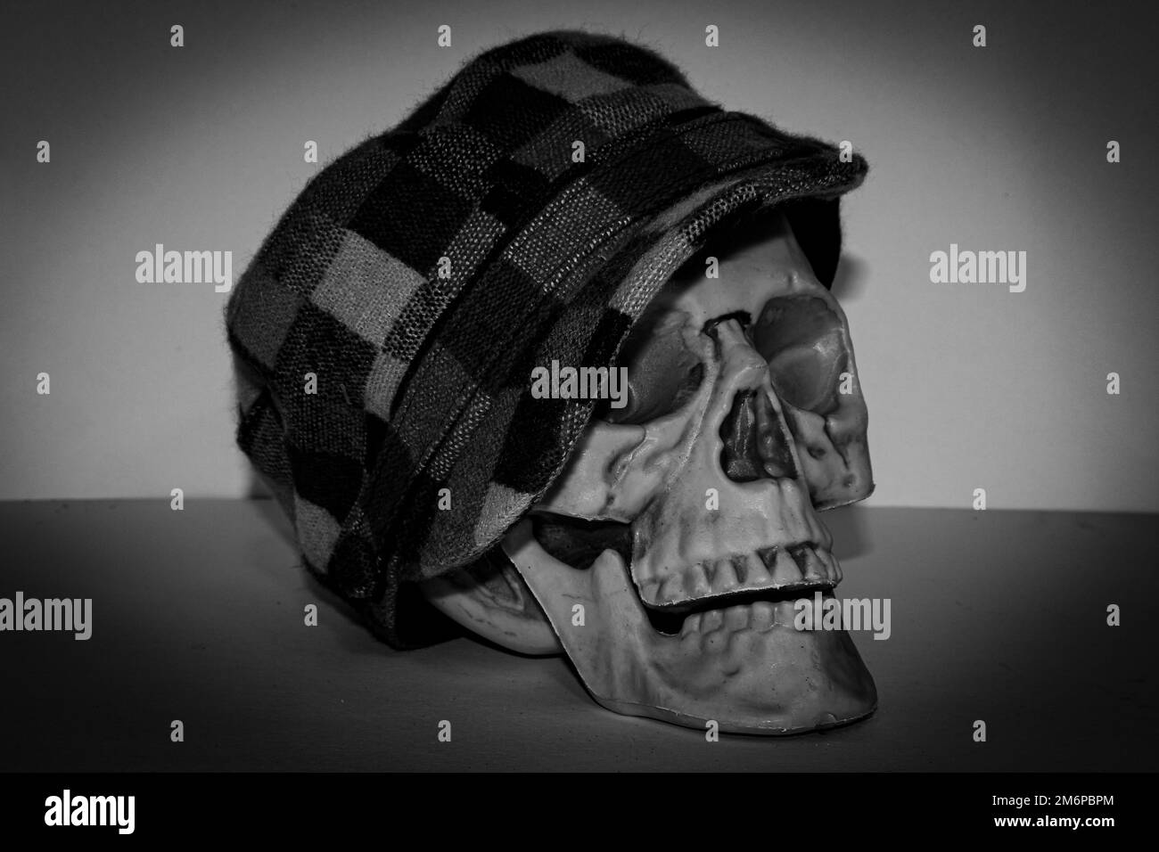 Black and White of a Skull wearing a checkered hat with a button Stock Photo