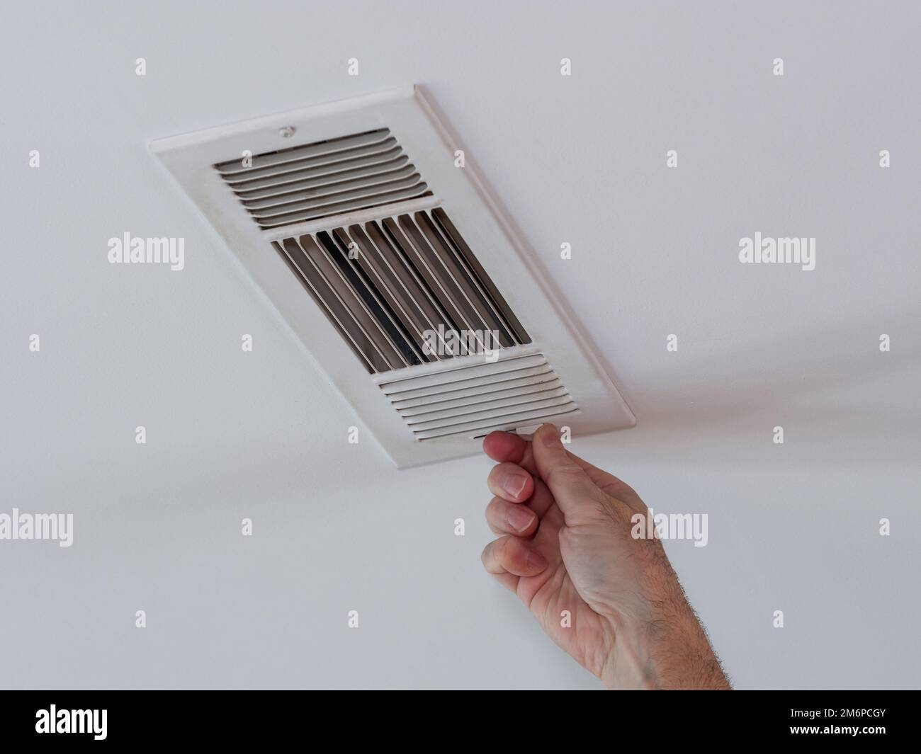 Handyman adjusting HVAC ceiling air vent. Air flow adjustment for overhead home heat and air
