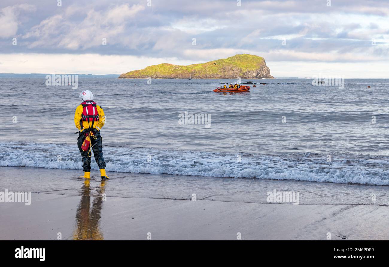 Royal National Lifeboat Institution (RNLI) inflatable boat and crew member on beach, Firth of Forth, North Berwick, East Lothian, Scotland, UK Stock Photo