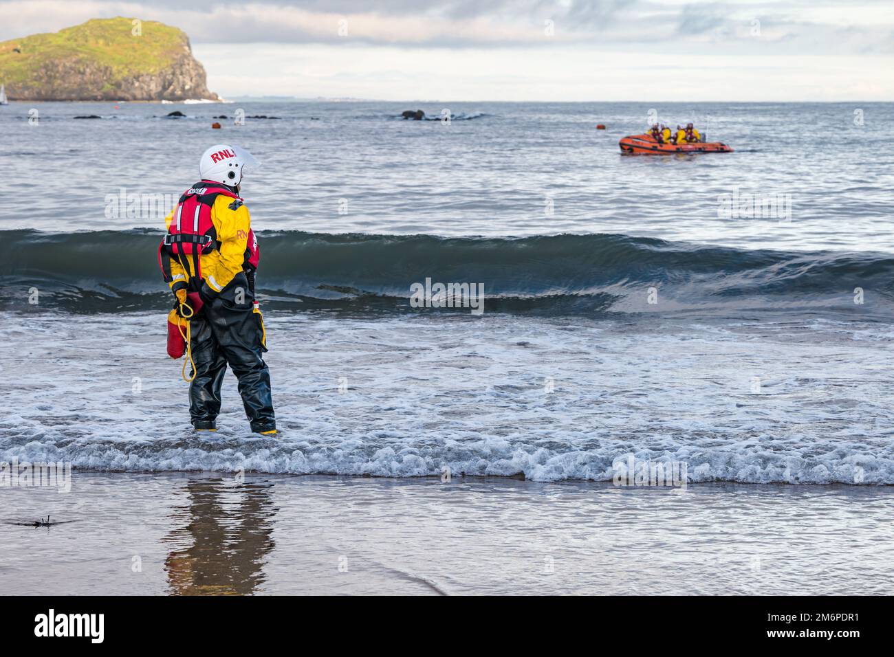 Royal National Lifeboat Institution (RNLI) inflatable boat and crew member on beach, Firth of Forth, North Berwick, East Lothian, Scotland, UK Stock Photo