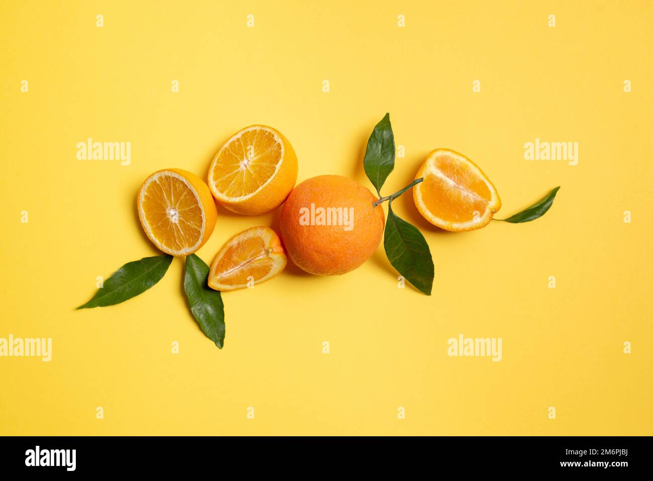 Orange fruit top view with slices on yellow background. Stock Photo