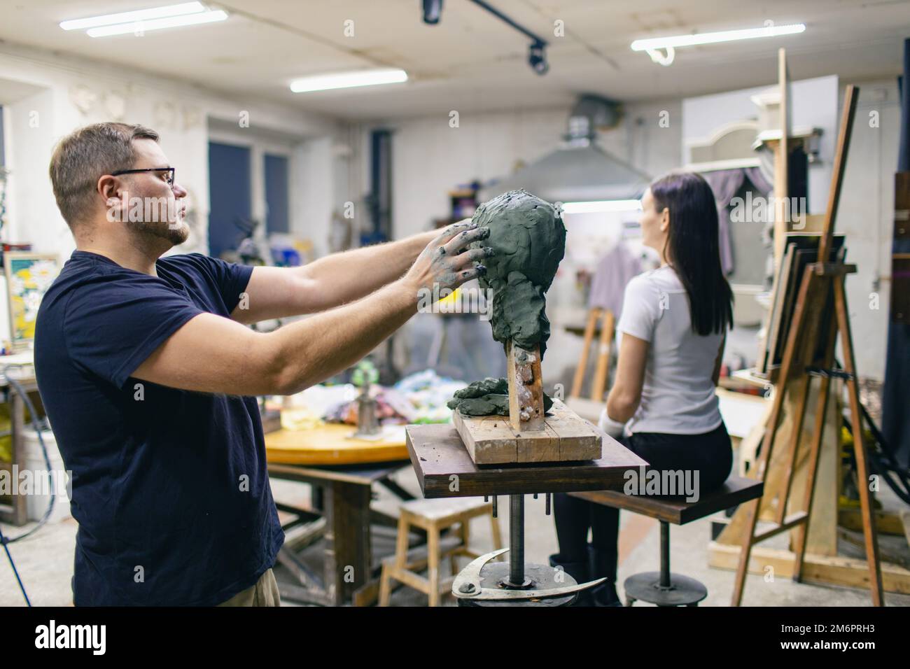 Man sculptor creates sculpt bust clay human woman sculpture. Statue