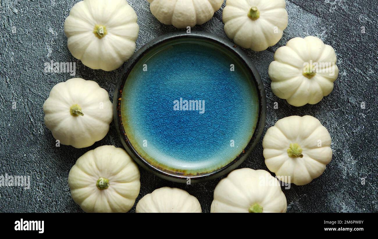 Small white Baby boo mini pumpkins placed in circle with blue ceramic bowl in the middle Stock Photo