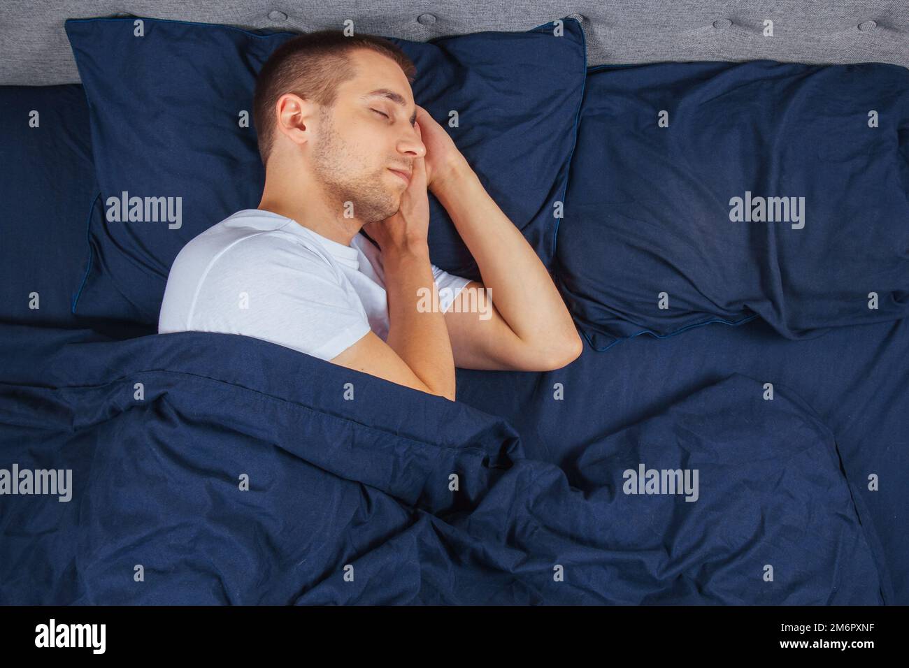 Top View Of A Handsome Young Man Sleeping Comfortably On The Bed At