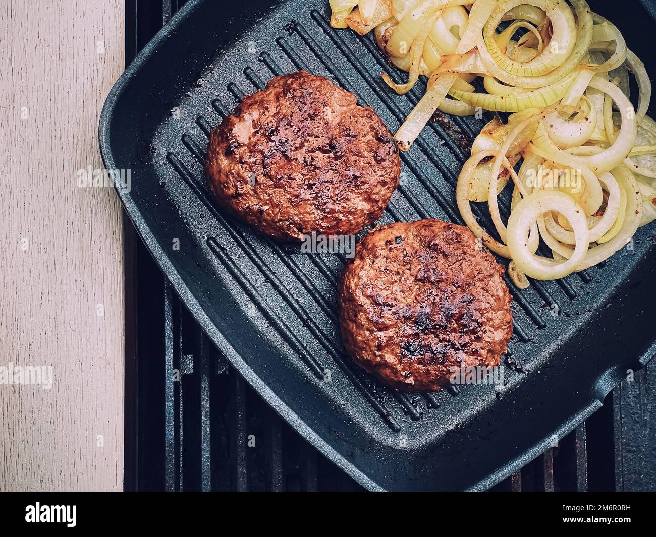 Cooking minced beef burger on cast iron grill skillet outdoors, red meat on frying pan, grilling food in the garden, English cou Stock Photo